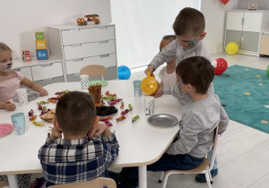 dzieci przy stoliku aranżują przyjęcie